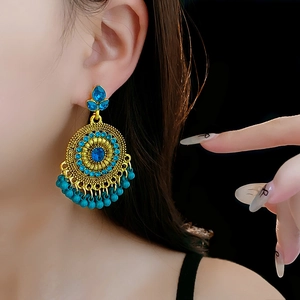 Detail of vintage gold earrings with blue rhinestones and turquoise beads on model