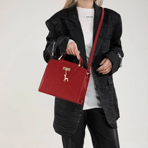 Red crocodile pattern handbag with gold deer charm and top handle on model