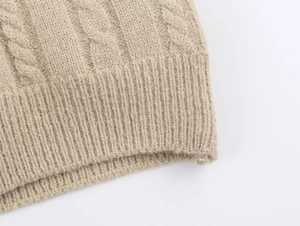 Detailed macro view of apricot cable knit vest with ribbed hem and wool texture