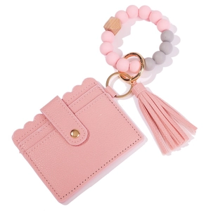 Detail of pink silicone bead bracelet with leather card holder and fringe tassel charm