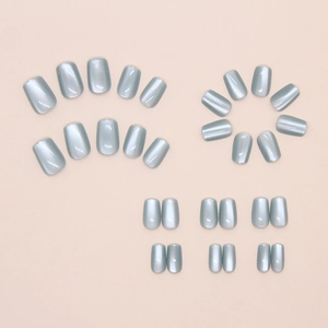 Detail view of emerald green cat-eye press-on nails in various sizes on pink background