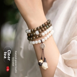 Macro detail of green sandalwood and white bodhi root prayer beads with metal charms