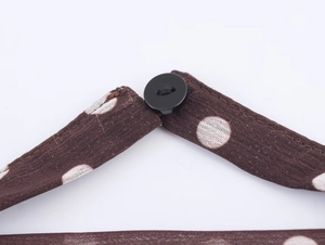 Gros plan sur le tissu marron à pois blancs et bouton noir de ce haut tendance