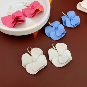 Detailed macro view of colorful matte flower drop earrings in blue, white and pink