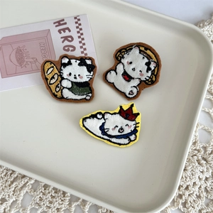 Close-up of embroidered cartoon cat patches with headphone and crown on white tray
