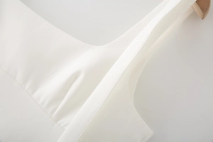 Macro shot of white bow strap dress neckline showing fine fabric texture and stitching