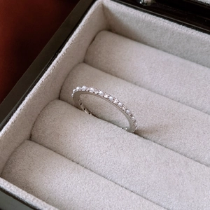 Primer plano de anillo de perlas plateado con diamantes pavé en estuche de terciopelo gris