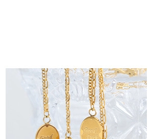 Detailed macro view of gold necklace pendants engraved with Good Luck hanging on glass