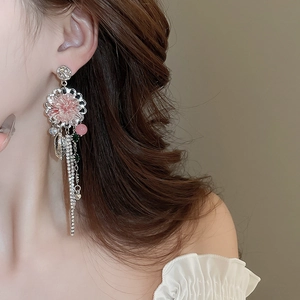 Close-up of elegant flower tassel earrings with pink crystals on model's ear