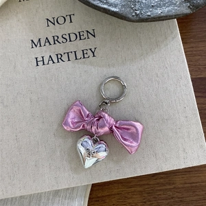 Pink ribbon bow with silver heart pendant keychain accessory on a minimalist background