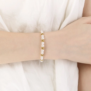 Close-up of elegant woven pearl and gold bead bracelet worn on a woman's wrist