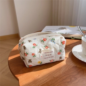 Quilted cotton makeup bag with cute bear pattern on a wooden table with soft sunlight
