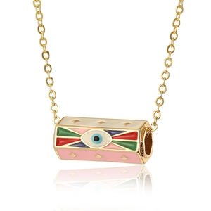 Macro shot of gold cylinder pendant with colorful evil eye enamel and embossed stars