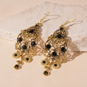 Macro detail of vintage gold hollow-out drop earrings with black rhinestones and flower tassels