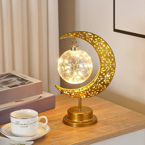Lampe de table lune dorée avec guirlande LED posée sur un bureau en bois chaleureux