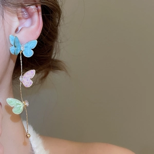 Detailed view of long butterfly drop earrings with zircon accents and gold chain on ear
