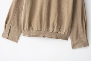 Detail of camel suede jacket featuring elastic hem and buttoned cuffs close-up