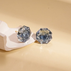 Detail of blue-grey geometric faceted glass stud earrings with gold-plated metal base