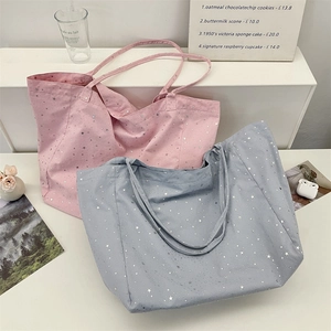 Detail of pink and grey canvas tote bags with silver star print in a lifestyle setting