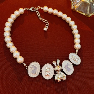 Choker di perle vintage con ciondoli a forma di coniglio su sfondo di tessuto rosso scuro