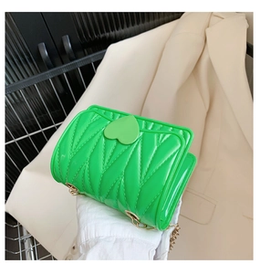 Detail of a bright green mini silicone heart bag with gold chain and heart buckle