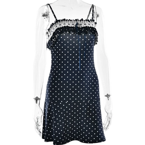 Detail of navy blue polka dot mini dress featuring white lace trim and front tie design