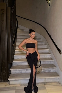 Detail of elegant black high-waist maxi skirt with 3D flower and thigh-high split