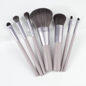 Detailed flat lay of 7 soft gray-purple gradient makeup brushes with matte handles