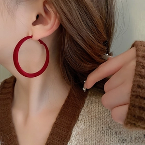 Close-up of model wearing large burgundy flocked geometric round hoop earrings