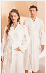 Detail of white unisex plush bathrobe featuring soft texture with belt and front pockets