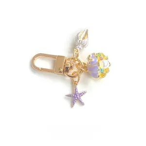 Detail of marine-themed keychain with purple starfish, seashell charms and golden clasp