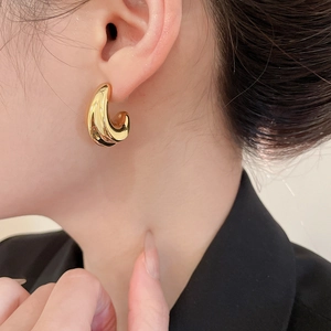 Close-up of a model wearing minimalist chunky gold teardrop hoop earrings for women