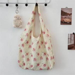 Close-up of floral embroidery detail on canvas tote bag with wide shoulder strap