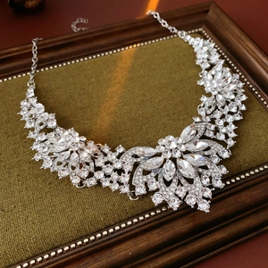 Macro shot of silver crystal flower necklace set on a dark green vintage frame background