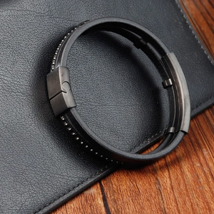 Detail of black woven leather bracelet with metal clasp on a textured wallet background