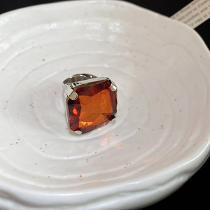 Macro detail of large square orange gemstone set in a polished silver ring mount