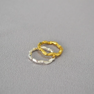 Minimalistische gehämmerte Wellenringe in Gold und Silber auf grauem Stoff