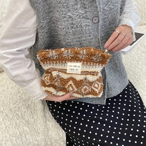 Close-up of a winter plush cosmetic bag with snowflake pattern and woven label
