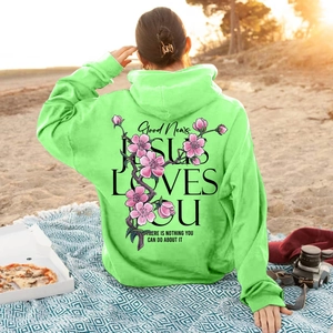 Neon green hoodie with pink floral print and Jesus Loves You text on beach