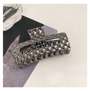 Detailed view of a black metal hair claw clip with stylish quilted texture on white surface