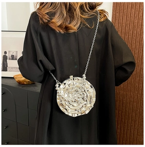 Silver metal rose-shaped crossbody bag with a delicate chain strap on black suit