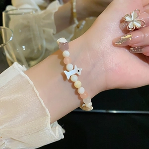 Détail d'un bracelet en perles d'oeil de chat avec breloque chien sur poignet femme