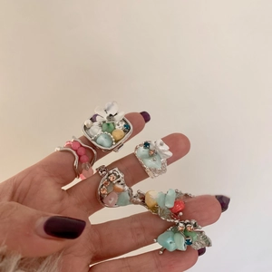 Detailed macro shot of vintage beaded flower rings with colorful stones on hand