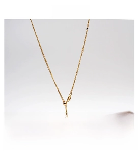 Détail d'un collier en Y doré réglable avec perle blanche sur un plateau à bijoux