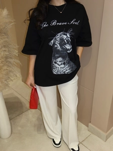 Dettaglio della t-shirt nera ampia con stampa leopardata e scritta decorativa
