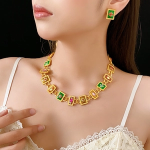 Detail of vintage enamel necklace and earrings set with colorful gemstones on a model
