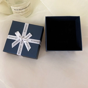 Detail of a dark blue jewelry gift box with branded ribbon and soft black velvet interior
