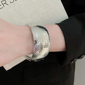 Detail of silver hammered finish on wide metal cuff bracelet with industrial design