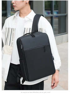 Detail of black minimalist backpack showing built-in USB charging port and matte fabric