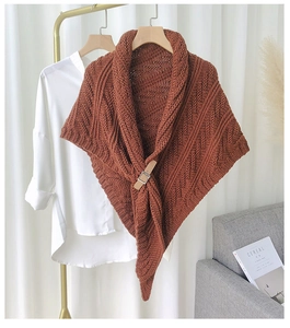Knitted caramel shawl detail showing thick knit texture and metallic buckle on shirt